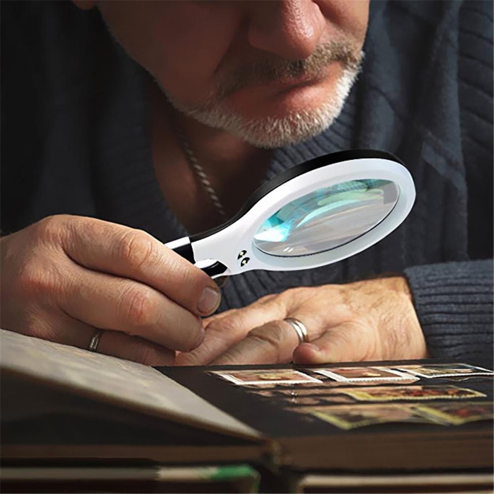 Older male using a magnifying glass while viewing a photo book